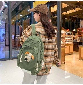 Detail of green corduroy backpack featuring 3D cartoon dog patch and large capacity