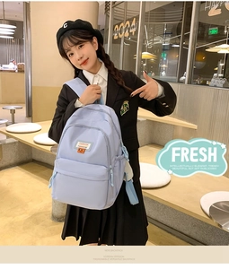 Close-up of a light blue student backpack with a FASHION patch on a model in a cafe