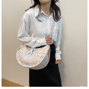 Detail of hand-woven orange and blue plaid texture on the half-moon crossbody bag