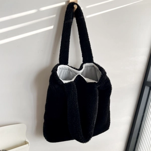 Detailed close-up of fluffy black faux fur tote bag with soft light gray lining detail