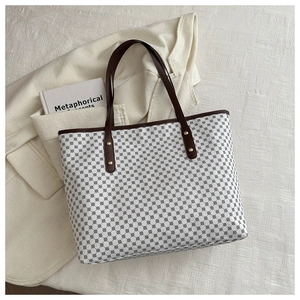 Detail of large tote bag with black geometric patterns and brown leather handles