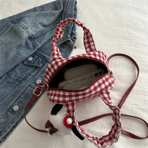 Red plaid canvas bowling bag for women with dog charm on white textured backdrop