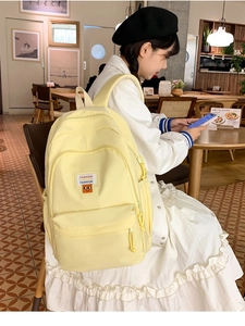 Detail of light yellow waterproof nylon backpack with fashion label and padded straps