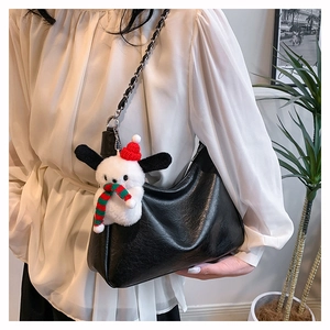 Detail of black faux leather crescent bag with chain strap and festive dog charm