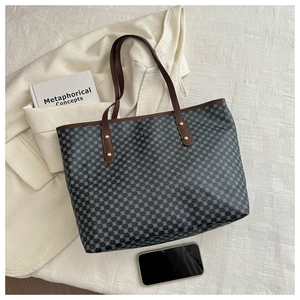 Close-up of a blue geometric pattern tote bag on a beige blazer with lifestyle props