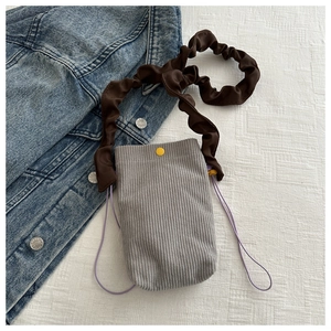 Detail of gray corduroy crossbody phone bag with brown ruffled strap and drawstring