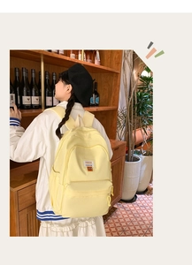 Detail of light yellow backpack with FASHION label on model in a cozy cafe setting