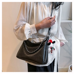 Detail of black pebbled PU leather shoulder bag with gold chain and Christmas plush charm