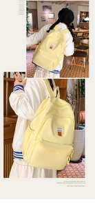 Detail of light yellow backpack with multiple zippers and fashion label in a cafe setting