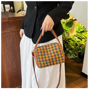 Detailed view of houndstooth tweed crossbody bag with plush handle and leather strap