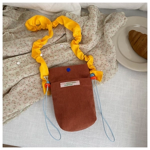 Close-up of corduroy phone bag with yellow ruffled strap and blue snap closure