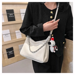 White textured leather shoulder bag with silver chain detail and plush puppy charm