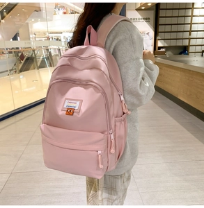 Pink nylon backpack detail showing side pockets and multi-layer zipper design on the bag