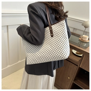 Detail of a large tote bag featuring black geometric circle patterns and brown leather handles