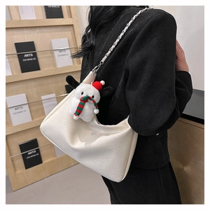 Close-up of white pleated tote bag with silver chain and cute puppy plush charm