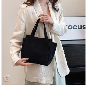 Detail of the black canvas tote bag showing the side pocket and sturdy handle texture