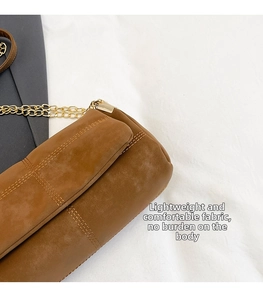 Close-up of brown suede crossbody bag with gold chain strap and fine stitching details