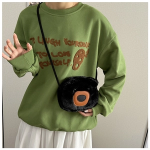 Détail du sac à bandoulière ours en peluche noir avec broderie sur le sweat-shirt