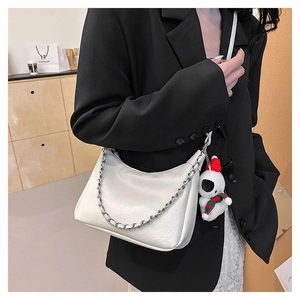 Detail of white pleated moon bag with silver chain and cute plush mascot pendant