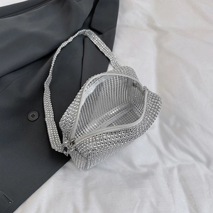 Elegant silver rhinestone handbag with shoulder strap placed on grey blazer background