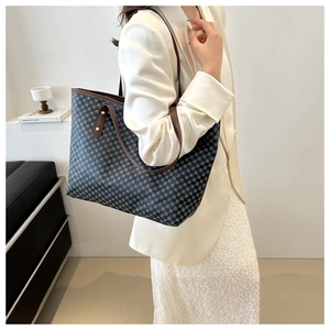 Detail of checkered tote bag featuring brown leather handles and gold metal rivets