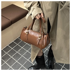 Détail d'un sac porté épaule en cuir marron avec boucles et fermeture éclair en métal