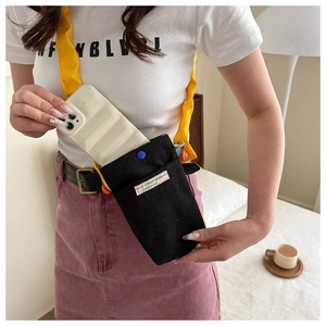Detail of black corduroy mini crossbody bag with contrasting yellow shoulder strap