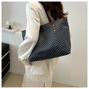 Detail of grey patterned tote bag with blue circles and brown straps worn on shoulder