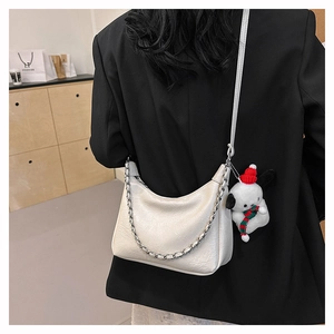 Detail of cream white leather shoulder bag with silver chain and cute plush pendant