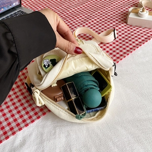 Canvas crossbody bag showing inner storage for phone, umbrella, and cosmetics