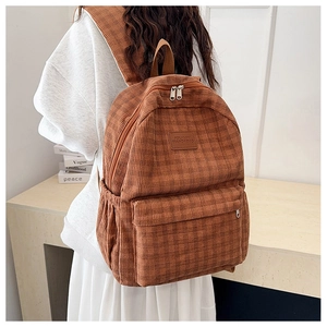 Brown corduroy backpack with vintage texture and double zippers worn by a student