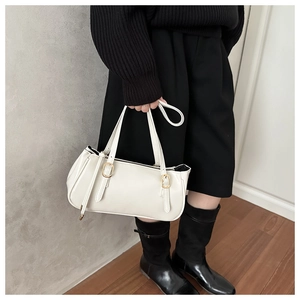 Macro shot of white minimalist handbag showing smooth leather texture and golden buckles
