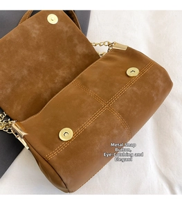 Detail of brown suede crossbody bag with gold magnetic snaps and quilted stitching