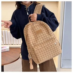 Detailed side view of a stylish brown plaid backpack with durable canvas and leather logo