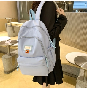 Detail of light blue nylon backpack with multiple zipper pockets and fashion label