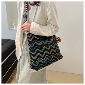 Detail of knit crossbody bag with colorful wavy patterns and cute bear charm