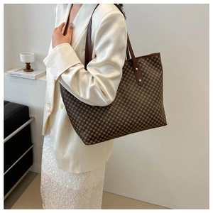 Detail of a large capacity brown monogram tote bag styled with a white satin blazer