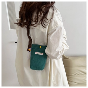 Detail of green corduroy mini phone bag featuring contrast yellow button and brand label