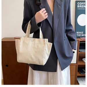 Detail view of a cream white corduroy tote bag with side pockets for daily commute usage