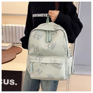 Detail of light green backpack featuring grey butterfly prints and dual side pockets