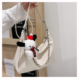 Detail of cream pleated tote bag with metal chain and festive puppy charm accessory