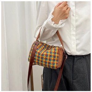 Detailed view of vintage houndstooth cylinder bag with leather handles and strap