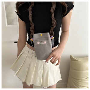 Detail of grey corduroy crossbody bag with ruffled shoulder strap and yellow snap button