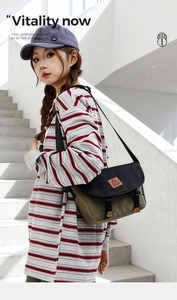 Detail of olive green and navy messenger bag with adjustable strap on a female model