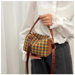 Detail of a vintage houndstooth cylinder bag with brown plush trim and gold hardware