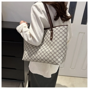 Detailed side view of large canvas tote bag with vintage pattern and leather straps