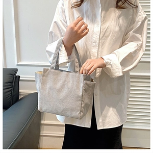 Detailed texture of grey corduroy handbag with dual handles for daily office commuting