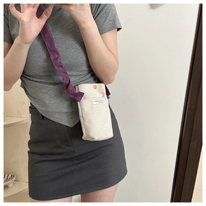 Detail of off-white corduroy mini crossbody bag with purple strap and fashion label