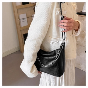 Detail of black textured leather shoulder bag with elegant silver chain decoration