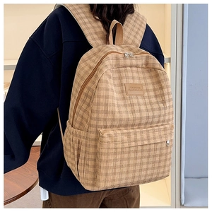 Detail of checkered corduroy backpack showing large front pocket and logo patch